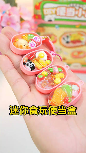 Miniature clay bento box charm held in a child's hand