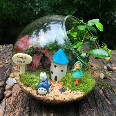 Miniature landscape terrarium with a tiny house built inside a glass bowl