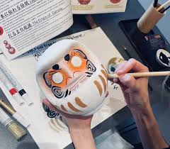 Child painting a small figurine with fine brushes in an art class