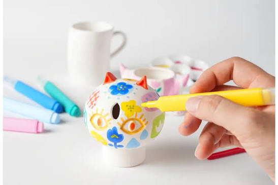 Child painting a ceramic mug with bright colors in an art class