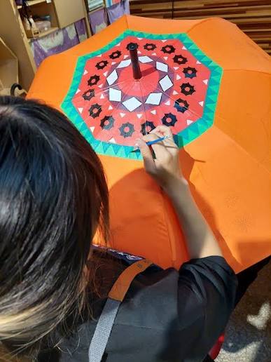 Child painting a colorful pattern onto fabric in an art workshop