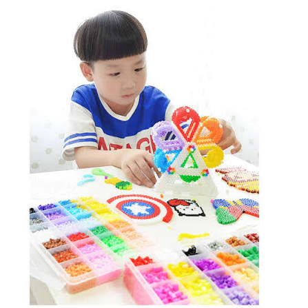 Boy placing perler fuse beads on a pegboard during a kids craft class in New York